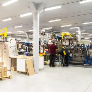 Equipment and Equipment Breakdown Insurance - Three men in a factory confer over a machine they are repairing.