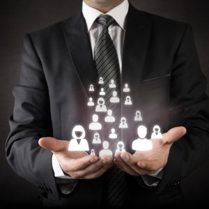 Group Benefits - Business person in suit holds a group of digital people icons in his hands.