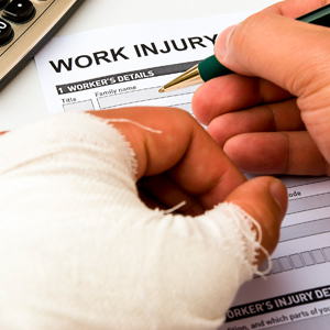 Workers Compensation Insurance - Image of a workers neatly bandaged hand as he fills a form for work injury.